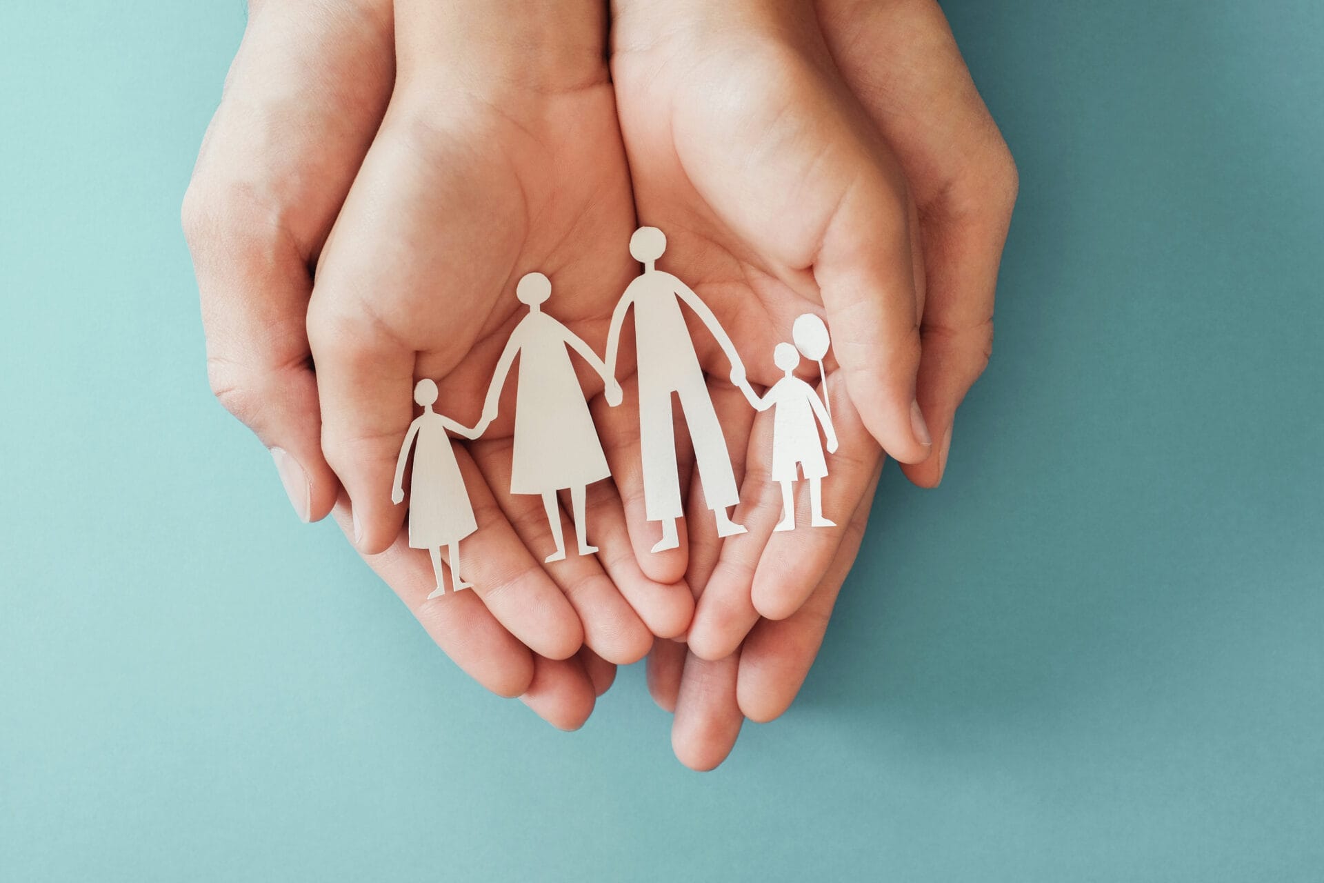 Adult and children hands holding paper family cutout.